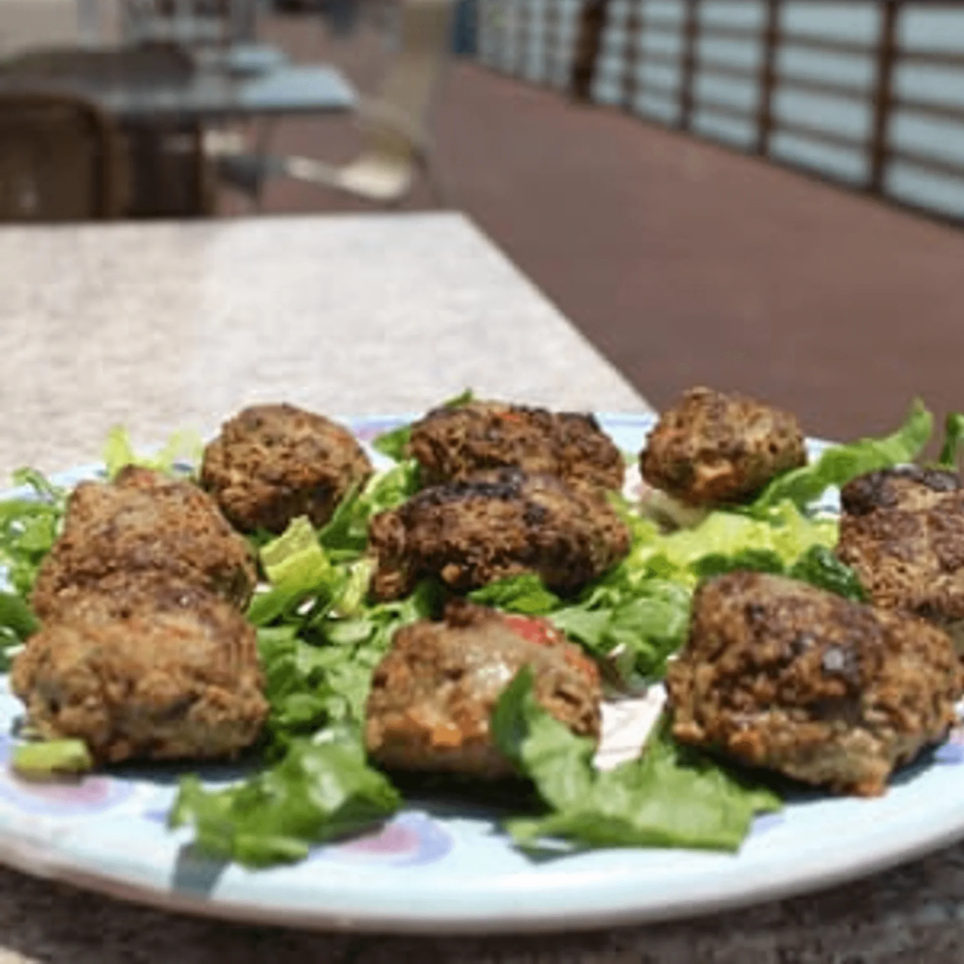 ShortyonDeck's American meatballs on a bed of lettuce, served on a patio table.